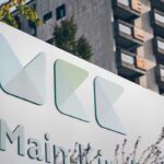 Ein Schild mit dem Main-Kinzig-Kliniken-Logo vor einem Hochhaus