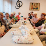 Viele Damen, die an einem Tisch sitzen und in die Kamera lächeln