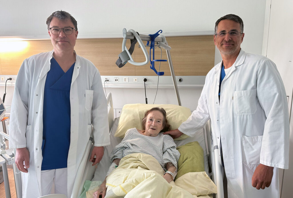 Zwei Mediziner stehen am Patientenbett einer älteren Patientin