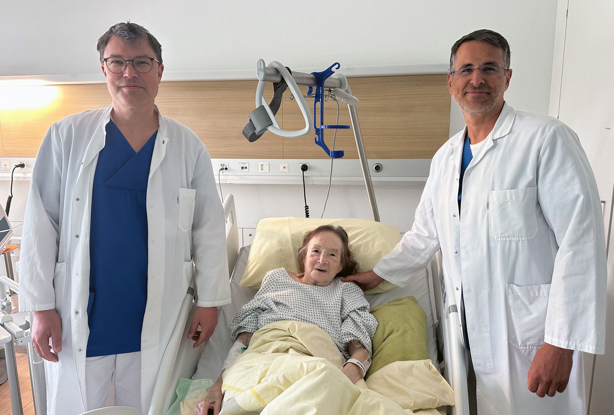Zwei Mediziner stehen am Patientenbett einer älteren Patientin