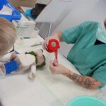 Eine Krankenpflegerin kümmert sich um das Kuscheltier eines Kindes.