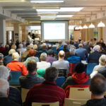 Dr. Andreas Schneider, Chefarzt für Urologie hält einen Vortrag zum Thema Männergesundheit in einem gefüllten Saal.